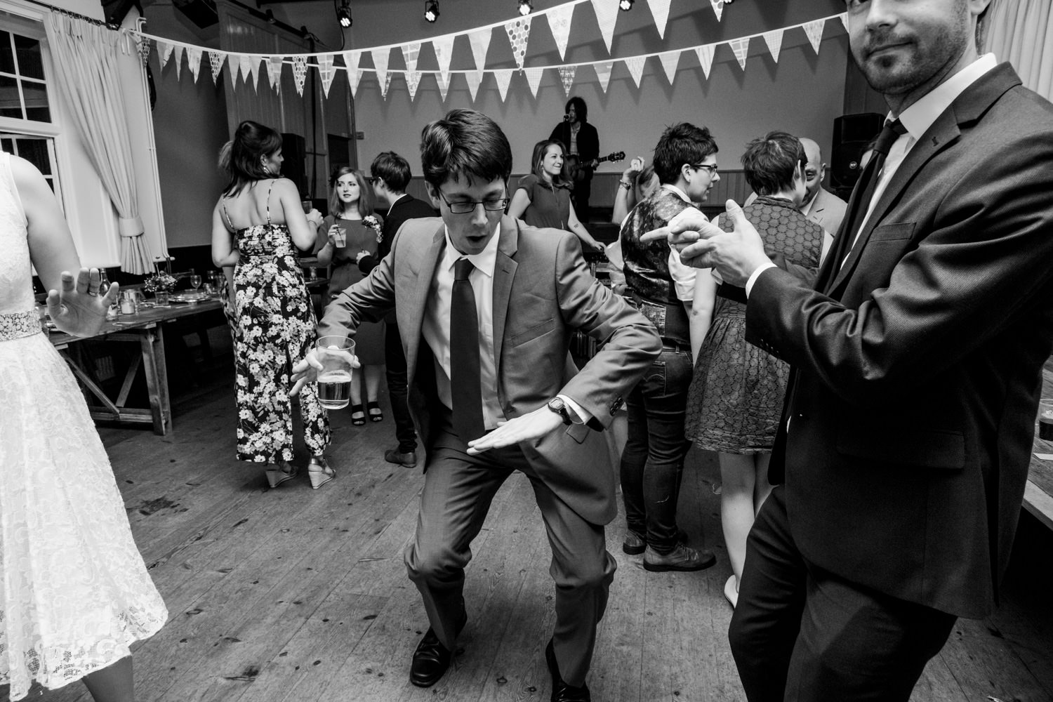 DIY Brighton wedding shot of male guest dancing with bunting in background